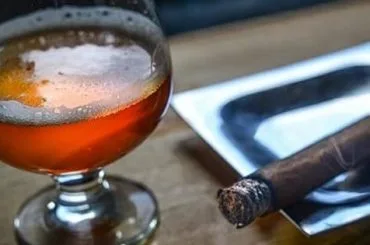 Cerveza en copa y puro encendido