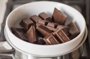 Chocolate Trozos de chocolate negro de alta pureza rompiéndose, listos para fundirse con mantequilla derretida.