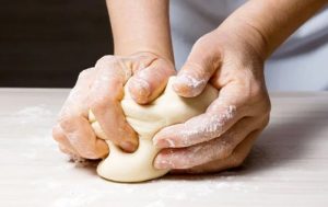 Masa de pan de muerto suave y elástica siendo amasada en un bol grande.