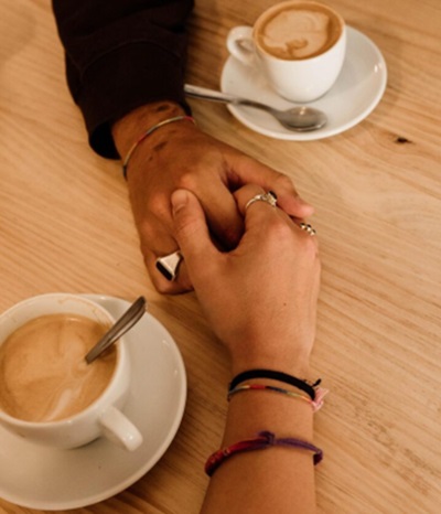 Pareja de la mano compartiendo un café