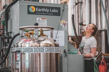 Operario ajusta una unidad de captura de CO2 Earthly Labs en una cervecería