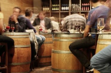 Grupo de personas conversa en la barra de un bar concurrido, escenario del efecto cóctel
