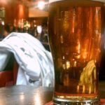Pinta de cerveza rubia sobre una mesa de pub