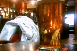 Pinta de cerveza rubia sobre una mesa de pub