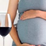 Mujer embarazada junto a una copa de vino tinto, el consumo de alcohol durante el embarazo