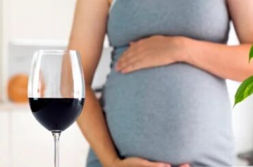 Mujer embarazada junto a una copa de vino tinto, el consumo de alcohol durante el embarazo