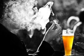 Hombre fumando mientras bebe cerveza, el consumo de alcohol y tabaco a la vez