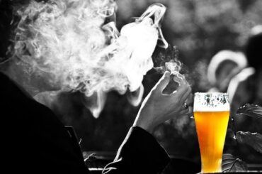 Hombre fumando mientras bebe cerveza, el consumo de alcohol y tabaco a la vez