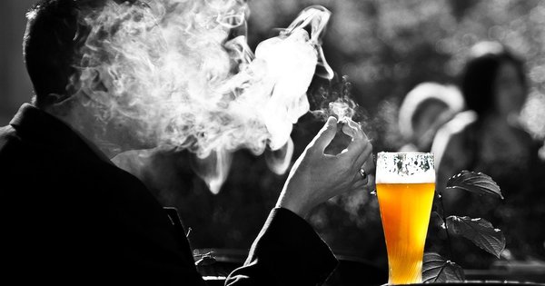 Hombre fumando junto a un vaso de cerveza Hombre fumando mientras bebe cerveza, el consumo de alcohol y tabaco a la vez