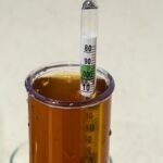 Densímetro flotando en una probeta con cerveza ámbar para medir la densidad y calcular la atenuación de la cerveza