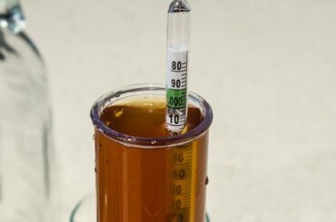 Densímetro flotando en una probeta con cerveza ámbar para medir la densidad y calcular la atenuación de la cerveza