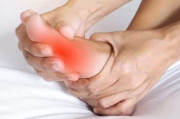 Persona sujetándose el pie con dolor en la articulación del dedo gordo, el síntoma típico de la gota