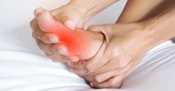 Person holding their foot in pain at the big toe joint, the typical symptom of gout