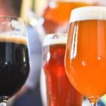 Three beers of different colors, a dark beer, a red beer and an amber beer, served on a table