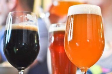 Three beers of different colors, a dark beer, a red beer and an amber beer, served on a table
